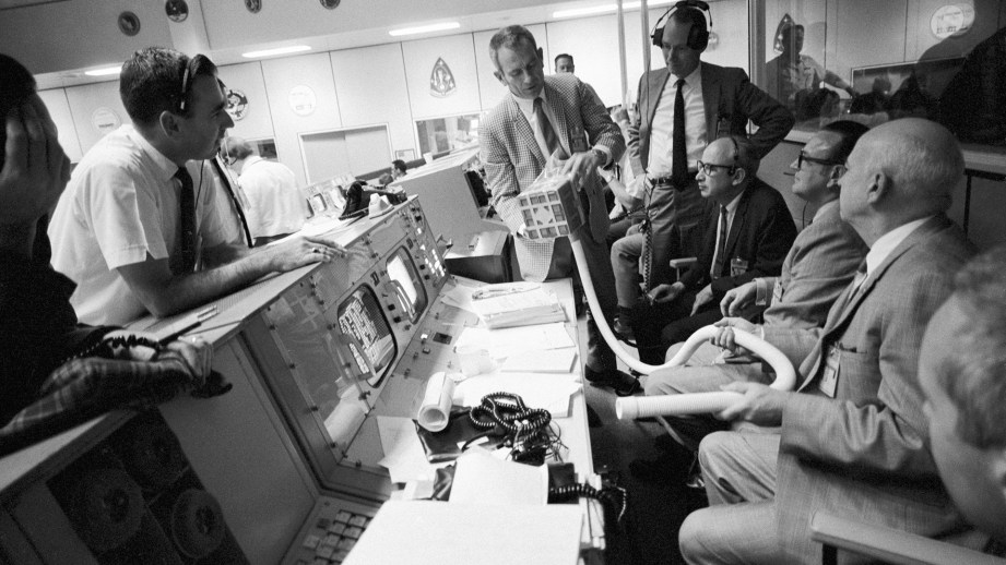 A crowd in mission control inspects the mailbox during the Apollo13 drama. The contraption was created on-the-fly to remove carbon dioxide from the lunar module.